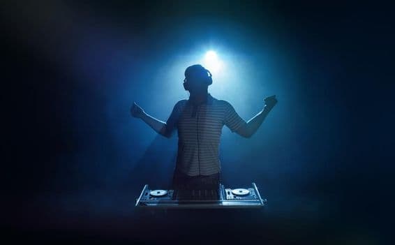 Человек стоит за диджейским пультом.