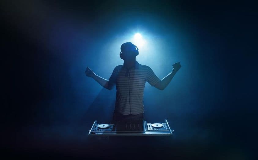 Человек стоит за диджейским пультом.