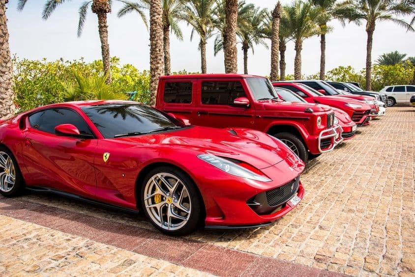 Роскошные красные автомобили, выстроенные в ряд в Дубае, включая Ferrari, Porsche, Mercedes.