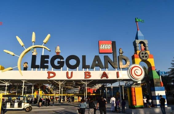 Вход в LEGOLAND Дубай с людьми и гольф-картом перед ним.
