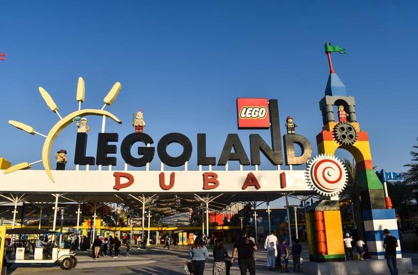 Вход в LEGOLAND Дубай с людьми и гольф-картом перед ним.