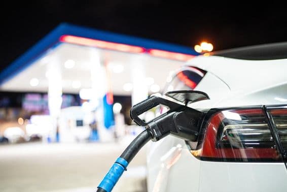 Зарядка Tesla с заправочной станцией на заднем плане.