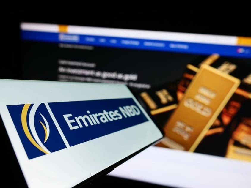 Знак Emirates NBD на переднем плане, на заднем плане инвестиционный золотой слиток.
