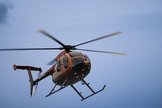 Лёгкий вертолёт летит в воздухе.