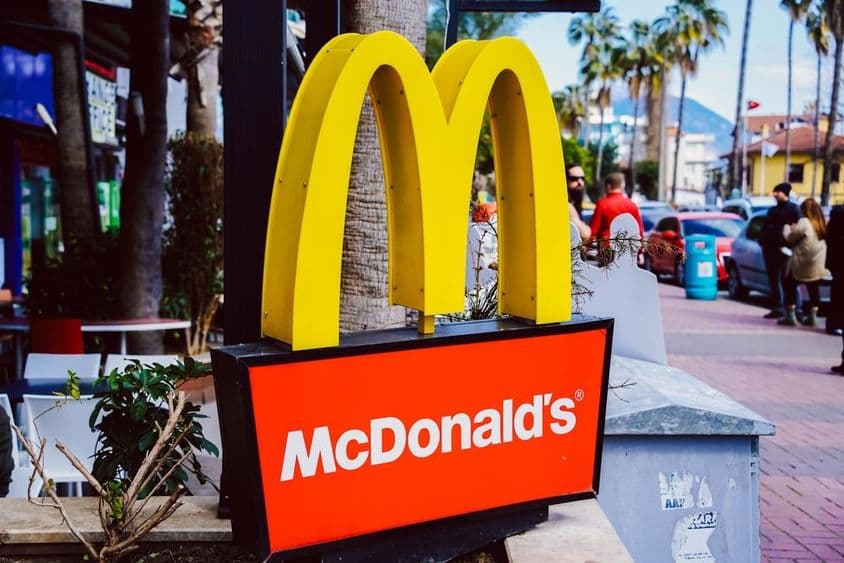 Знак McDonald's на фоне уличного вида.