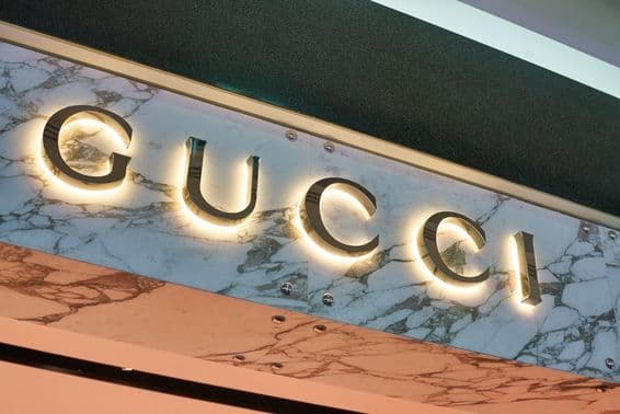 Вывеска Gucci в светящихся буквах на фасаде стены.