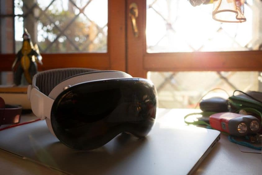 Apple Vision Pro лежит на тетради на столе.