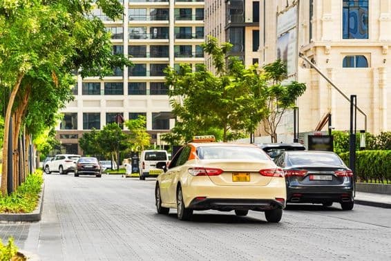 Дубайские автомобили на дороге, на переднем плане такси, на заднем плане дома.