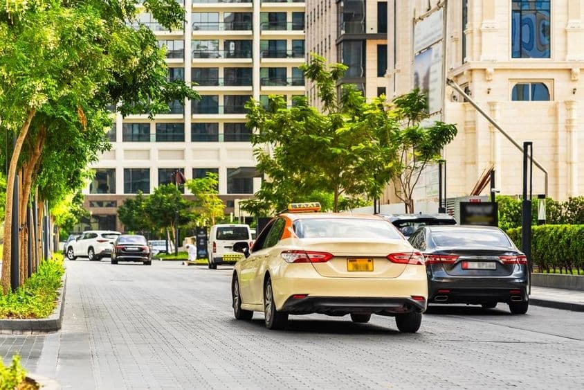 Дубайские автомобили на дороге, на переднем плане такси, на заднем плане дома.