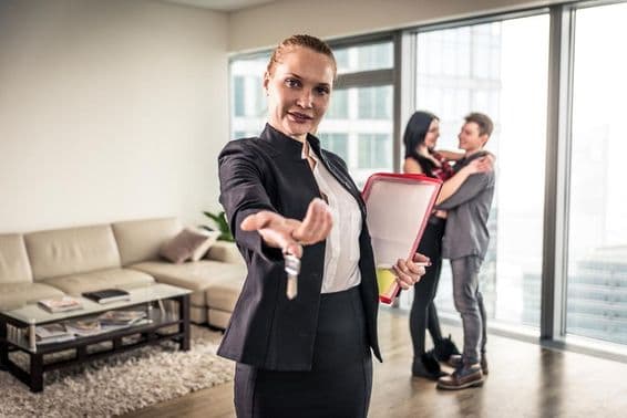 Женщина-брокер смотрит на экран, в фоне обнимается пара.