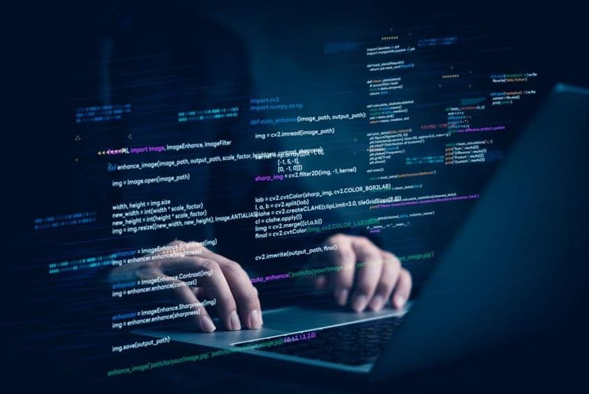 Блокнот с двумя руками, работающими над проекцией компьютерного кода.