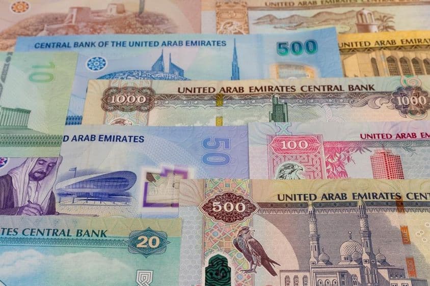 Банкноты номиналом 20, 50, 100, 500, 1000 дирхамов на столе.