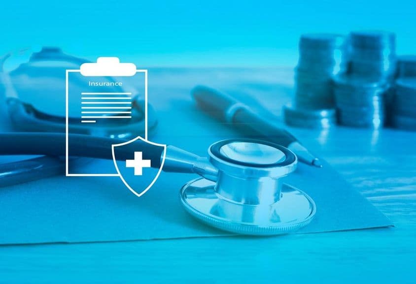 Медицинская страховка на переднем плане, на заднем фоне стетоскоп и мелкие деньги.