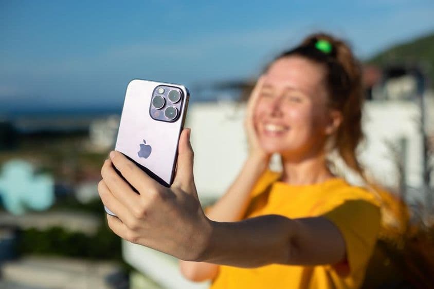 Молодая девушка держит телефон iPhone.