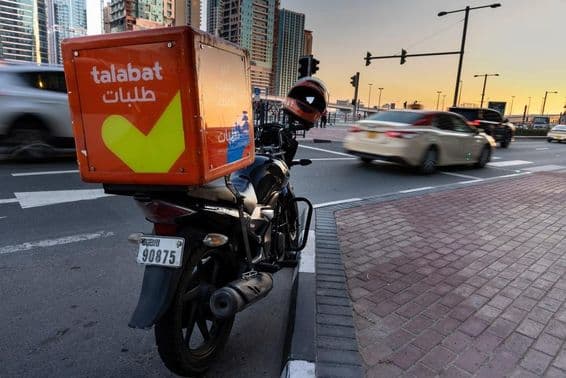 Мотоцикл Talabat припаркован на обочине дороги.