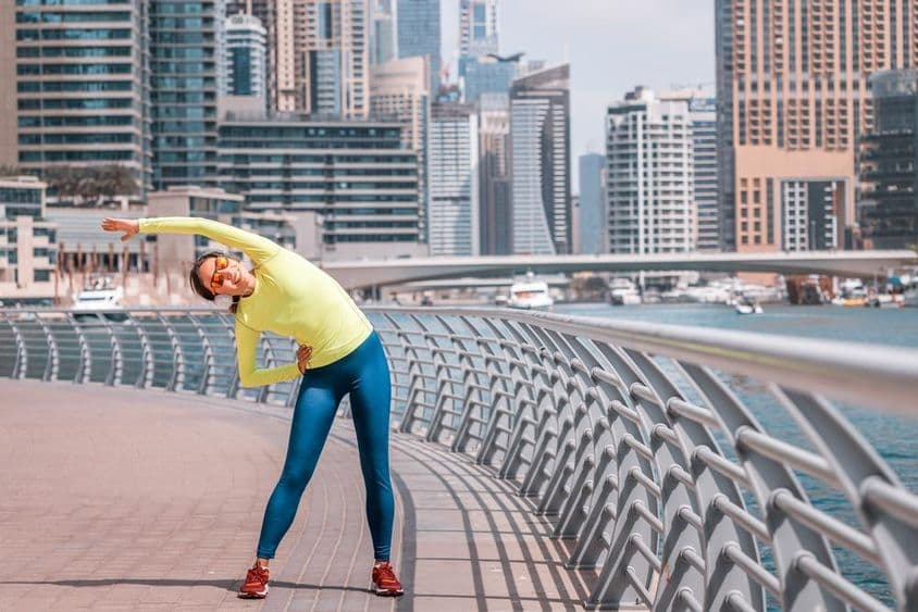 Юная девушка из Дубая выполняет растяжку после пробежки на Марине.