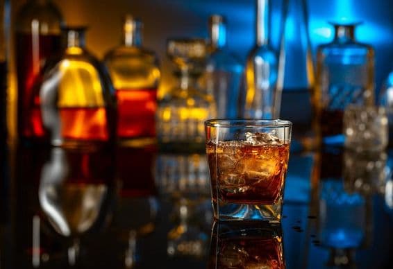 Виски с льдом на черном столе в баре.