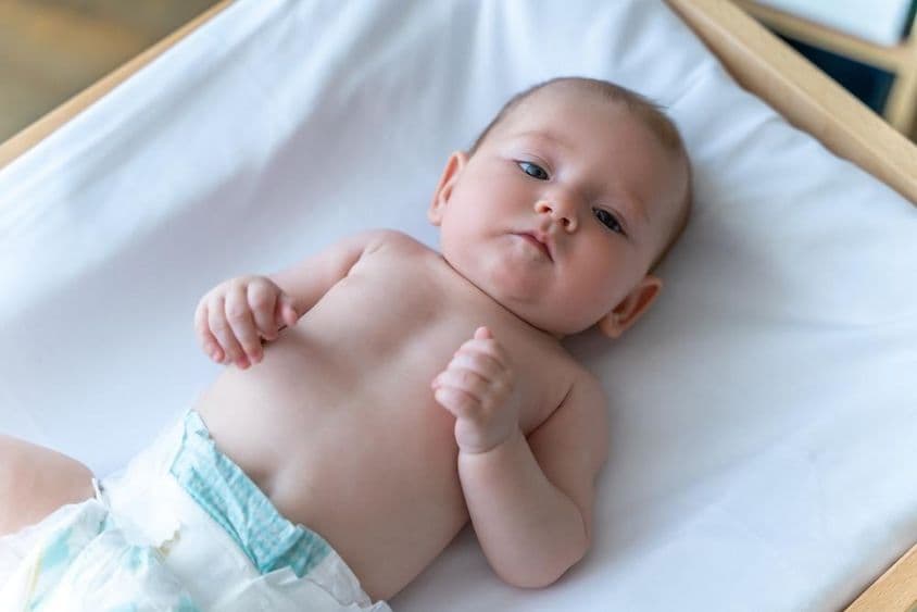 Белый младенец, лежащий в подгузнике.