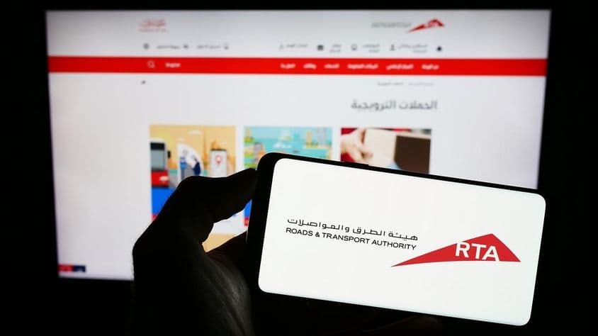 Логотип RTA на телефоне на фоне веб-сайта.