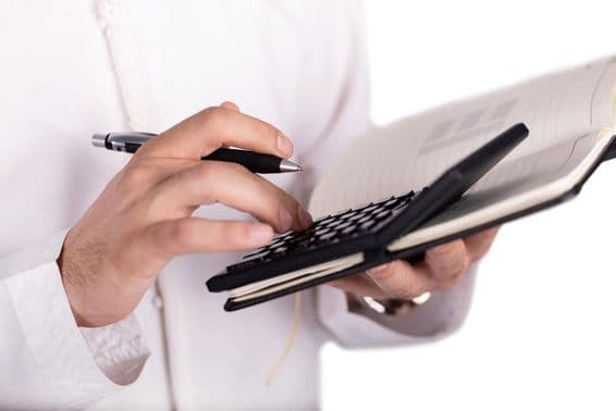 Арабский бизнесмен держит калькулятор.