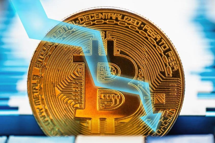 Золотая монета Биткойн - символ криптовалюты и стрелка, указывающая вниз на техническом фоне.