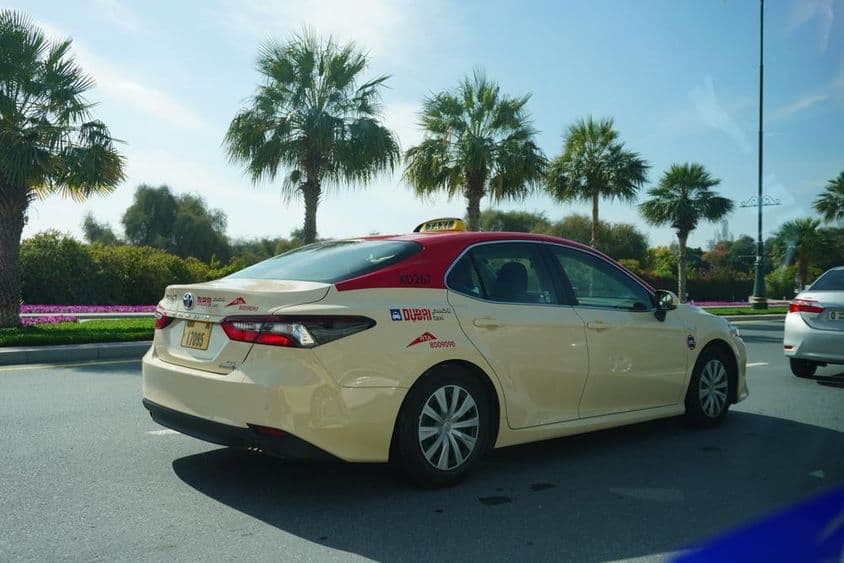 Дубайское такси с красной крышей едет по дороге.