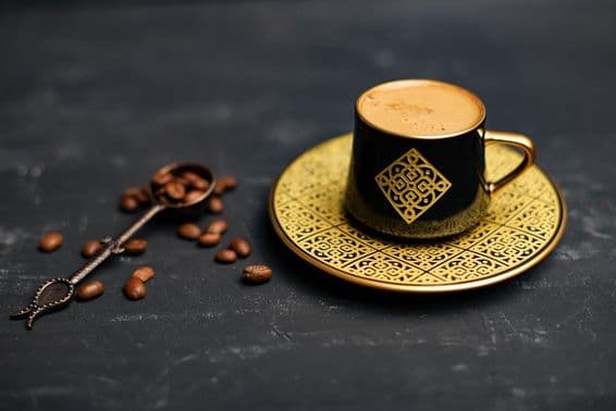 Золотая чашка кофе с блюдцем.