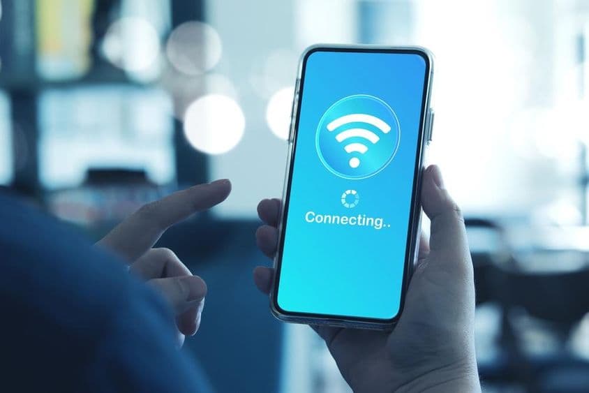 Мужчина использует смартфон для подключения к Wi-Fi на смартфоне.