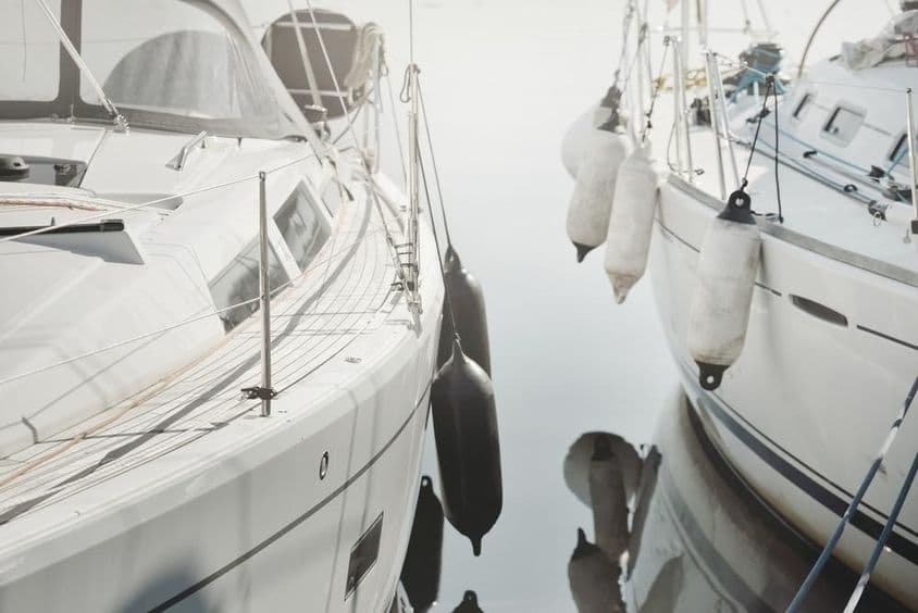 Современная белая парусная яхта, пришвартованная на пристани.