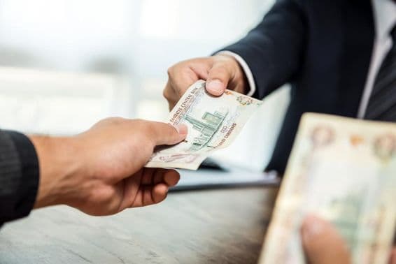 Бизнесмен передает деньги в валюте дирхам своему партнеру.