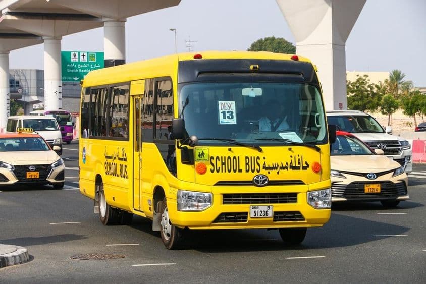 Школьный автобус Toyota Coaster на городской улице.
