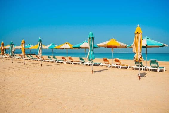 Дубай общественный пляж, песчаный берег, шезлонги и синее море.