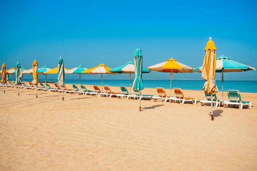 Дубай общественный пляж, песчаный берег, шезлонги и синее море.