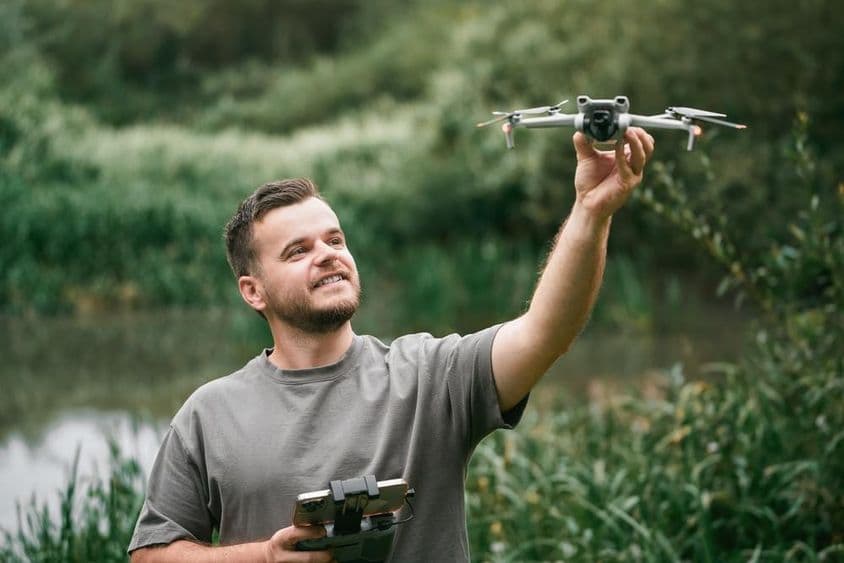 Инструктор с дроном в руке во время занятия на открытом воздухе.