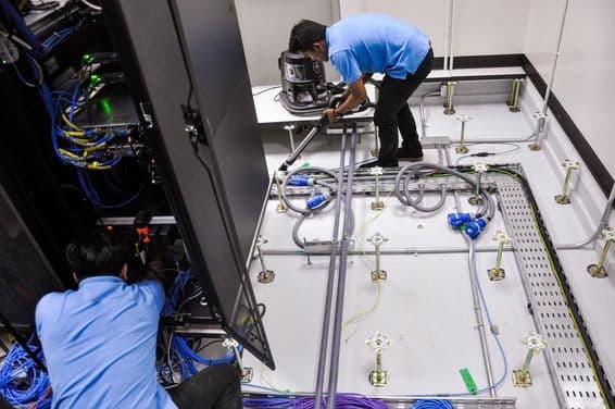 Рабочие строят серверную, поднятые полы и шкафы.