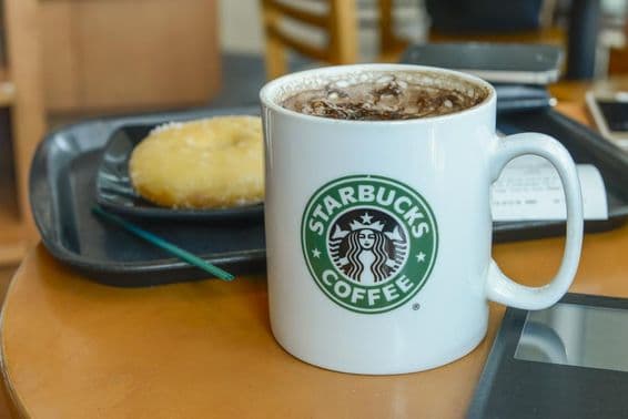 Какао капучино в горячей, парящей кружке в кафе Starbucks.