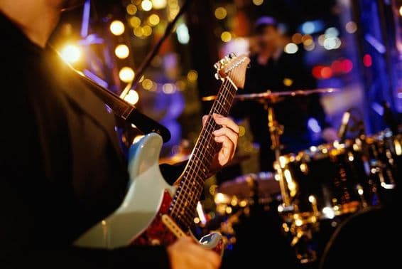 Гитарист играет аккорд на грифе во время выступления группы.