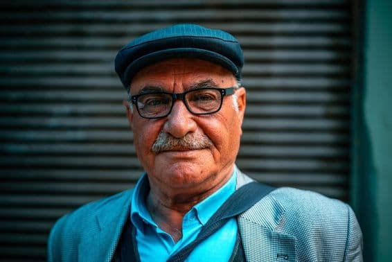 Пожилой мужчина в шляпе на улице.