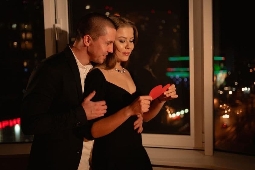 Влюбленная пара на свидании на День Святого Валентина, стоящая у окна.