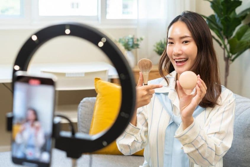 Молодая инфлюенсерка-блогер, использующая смартфон, говорит на видеоподкасте.