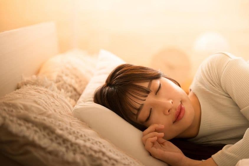 Женщина спит в постели.