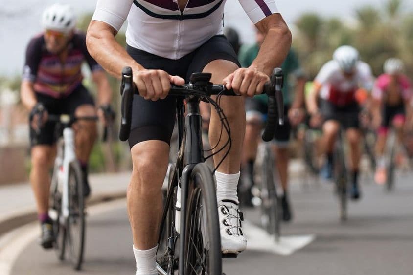 Спортсмены-велосипедисты на улице соревнуются.