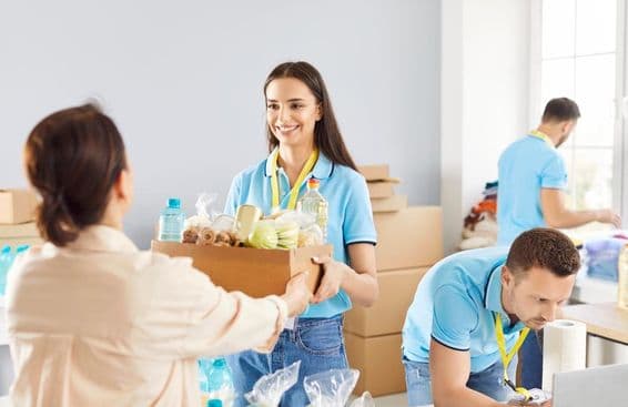 Молодой волонтер раздает бесплатные продукты тем, кто в них нуждается, в благотворительной организации.