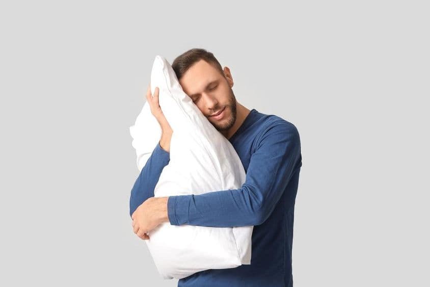 Молодой человек в пижаме с мягкой подушкой.