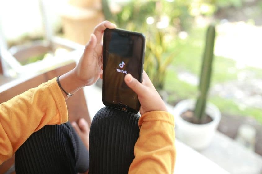 Ребенок просматривает контент TikTok на мобильном телефоне.