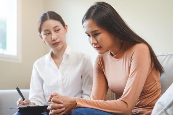 Печальная молодая азиатская женщина консультируется с психологом.