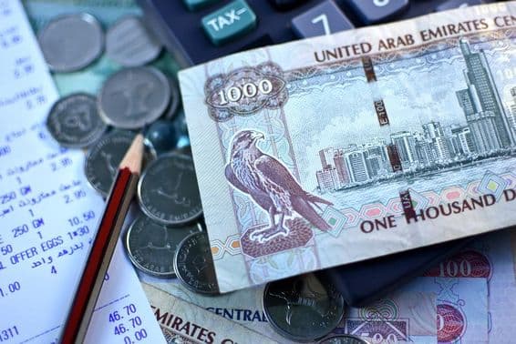 Банкнота ОАЭ в 1000 дирхамов и горсть монет.