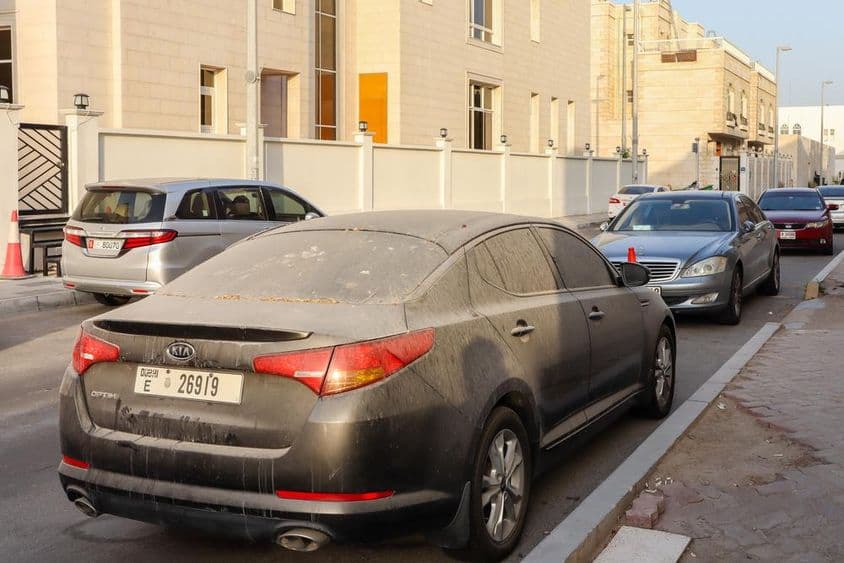 Пыльные и песчаные автомобили с номерными знаками Дубая, припаркованные в Абу-Даби.