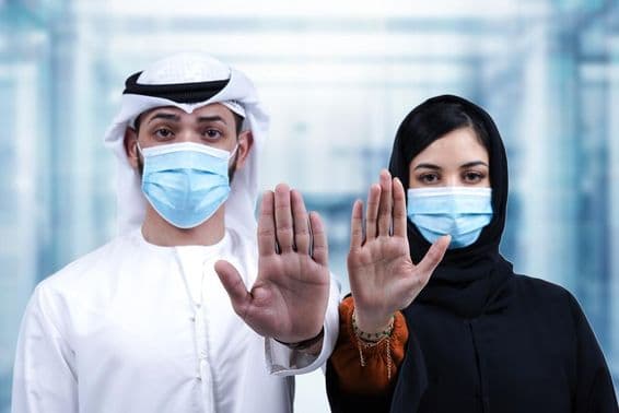 Арабский мужчина и женщина в медицинских масках показывают жест "стоп".