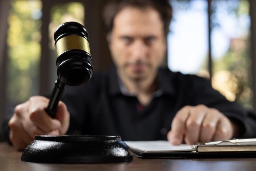 Судья, держащий молоток, сигнализирующий завершение судебного процесса.